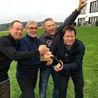 vier jubelnde Männer mit Wein