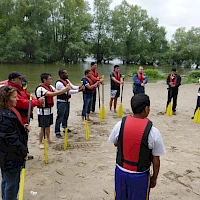 Team mit Paddeln am Ufer