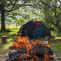 Lagerfeuer mit Zelt im Hintergrund